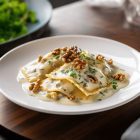 Assiette de raviolis frais Morini Pasta servis avec une sauce gorgonzola crémeuse et des noix croquantes.
