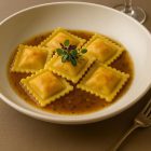 Ravioli Surf N Turf servis dans un bouillon raffiné – présentation gastronomique restaurant