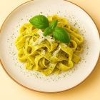 Assiette de tagliatelles au pesto garnies de basilic frais et copeaux de parmesan