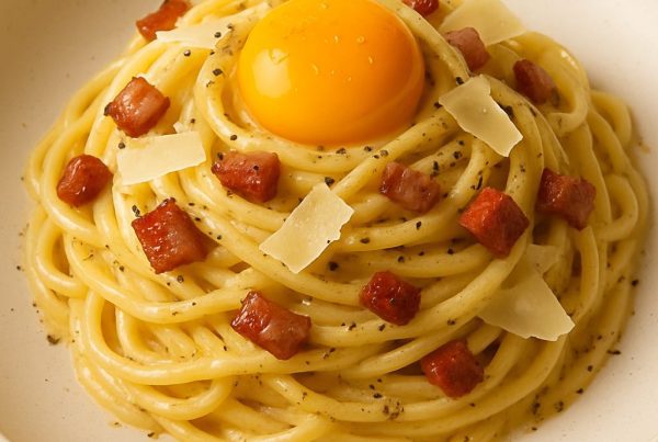 Assiette de linguini carbonara garnie d’un jaune d’œuf, pancetta et parmesan, présentation gastronomique.