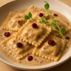 Raviolis nappés de sauce poivre et canneberges avec canneberges séchées et pousses de pois.